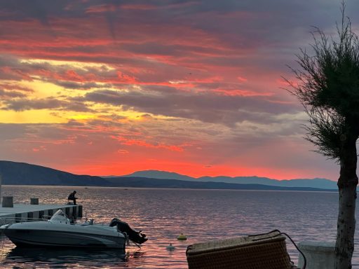 Boot am Ufer vor einem dramatischen Sonnenuntergang über dem Wasser